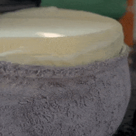 Personne ajustant une couche supplémentaire de rembourrage dans un lit pour animaux Comfy Wopiloo en peluche grise.